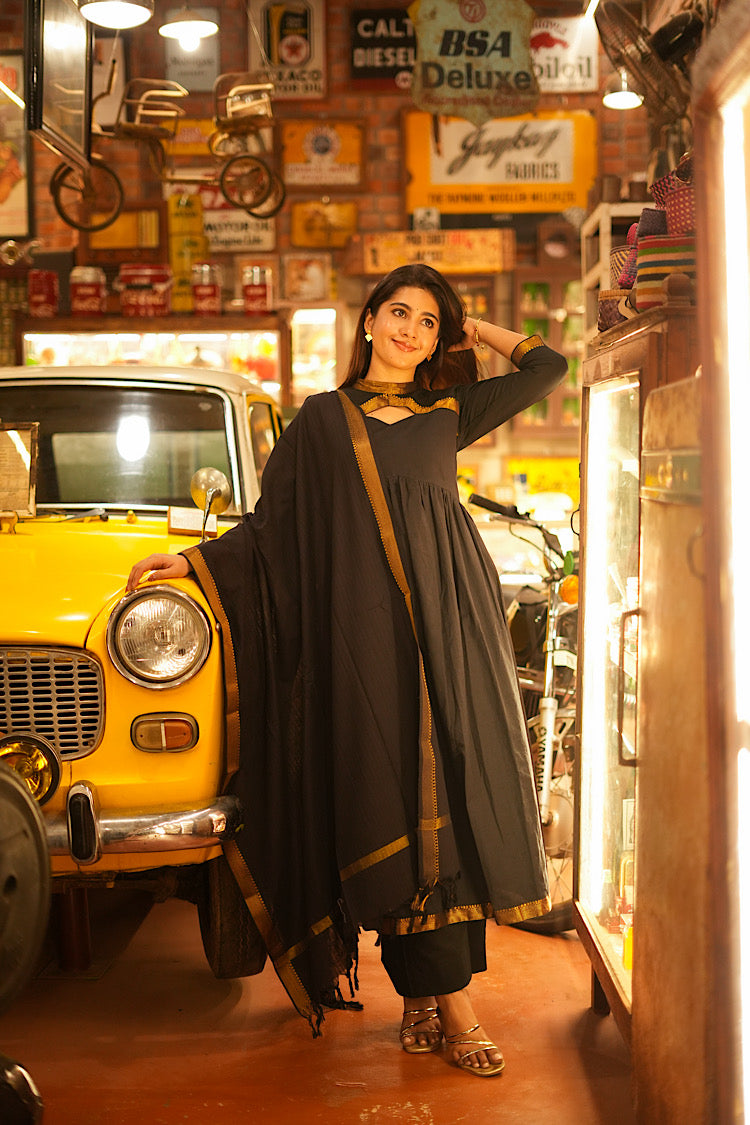 Three-piece black cotton anarkali kurti set with a zari-bordered dupatta draped over the shoulder.