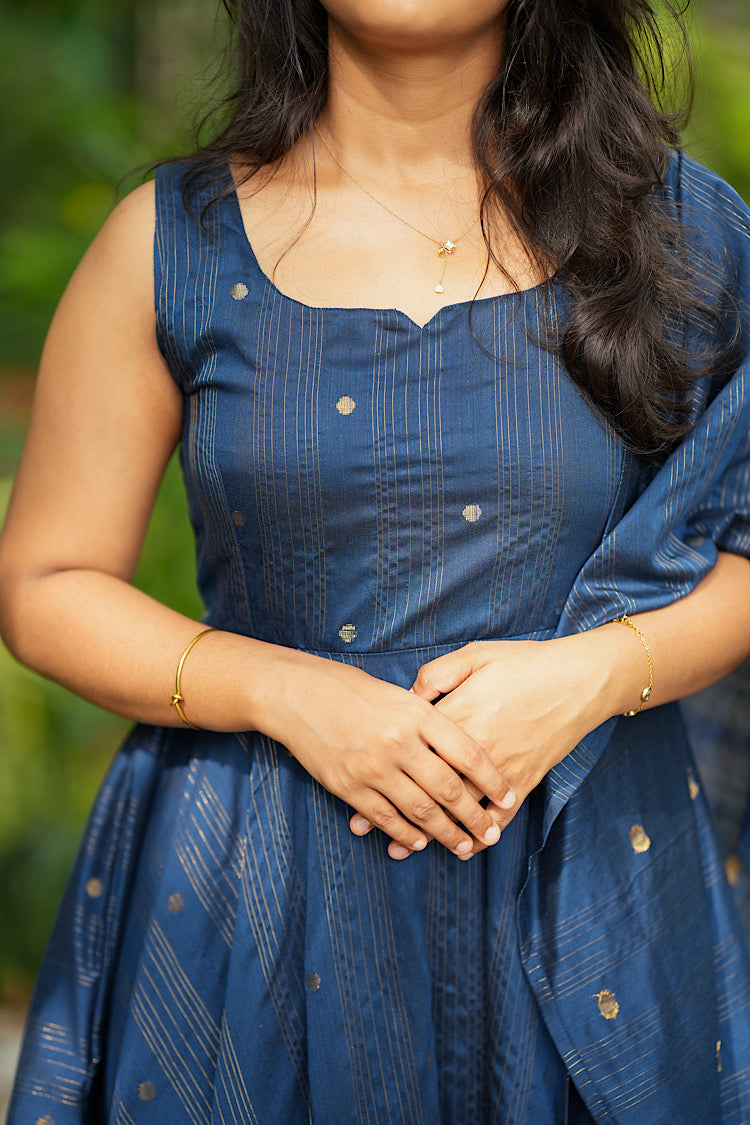 Close up view of gold zari woven stripes and small buttis on blue raw silk fabric