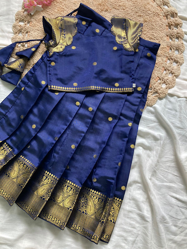 Flat lay of royal blue pattu pavadai set showing short sleeve top and pleated skirt with tassel details