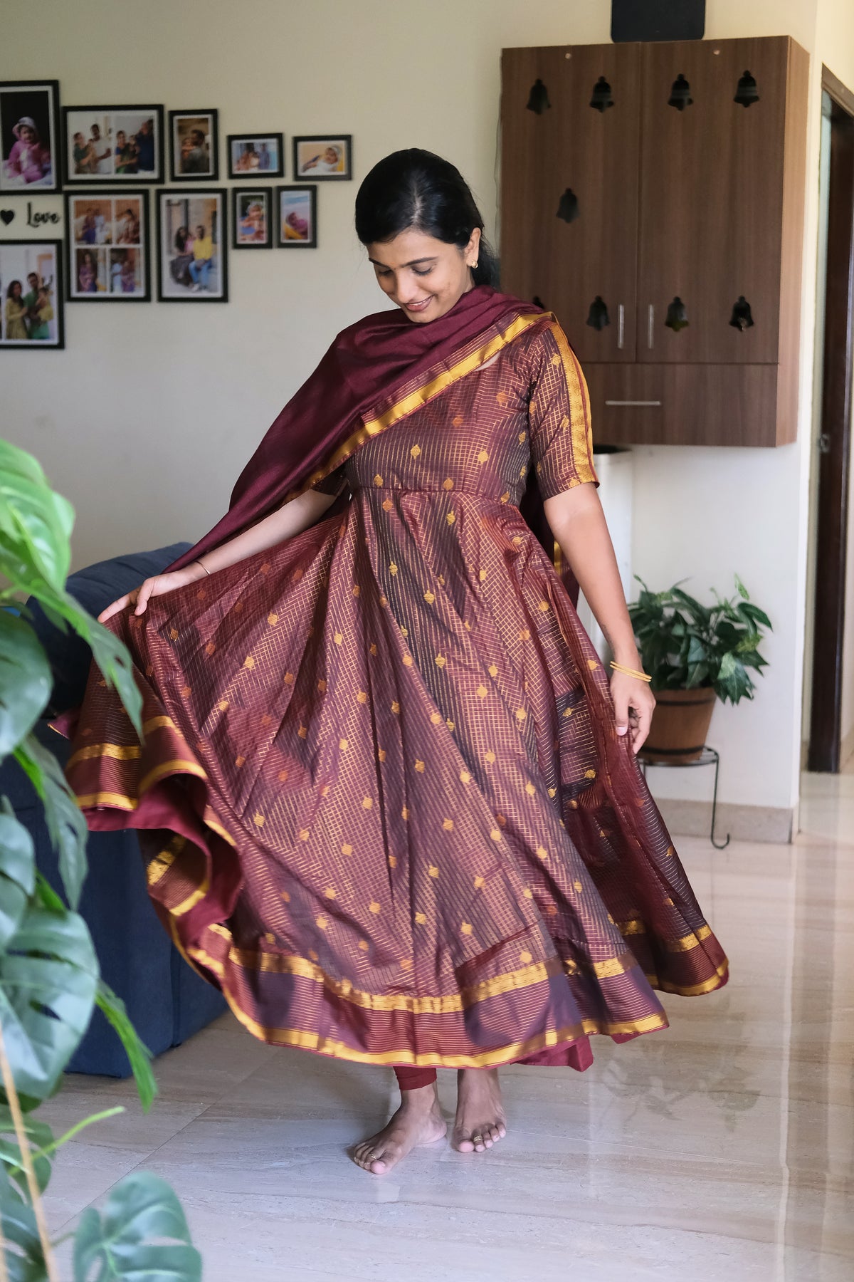 Twirling view highlighting the extensive flare and woven border hem of the maroon silk anarkali suit