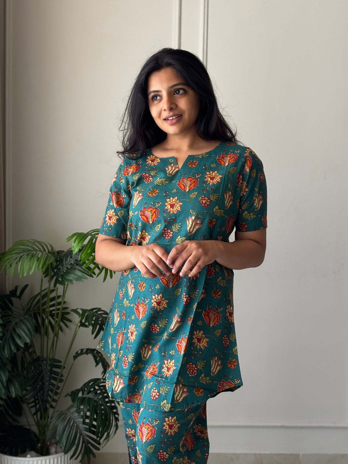 Close-up of the notched round neckline and vibrant floral print on the teal cotton night suit for women.