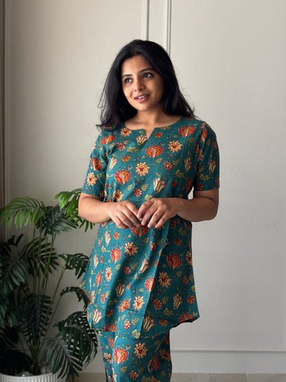 Close-up of the notched round neckline and vibrant floral print on the teal cotton night suit for women.