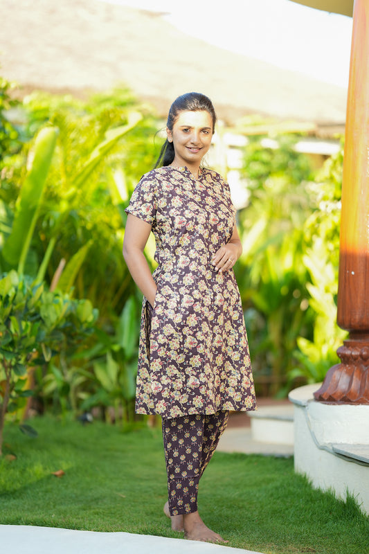 Model wearing the Krithi violet cotton night suit for women featuring a floral printed long top with pockets and matching pants.