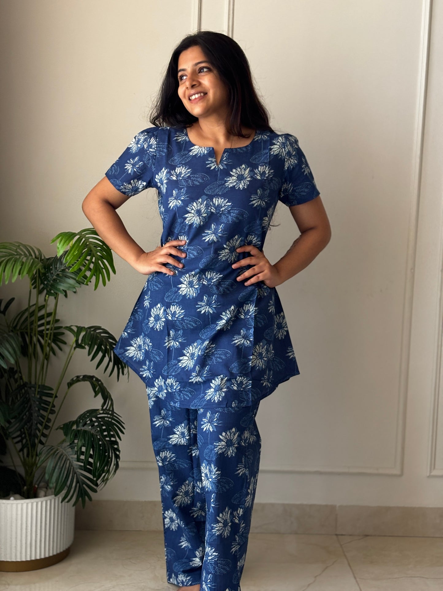 A blue floral cotton night suit for women featuring a tunic-length top with short sleeves and matching straight-fit pants.