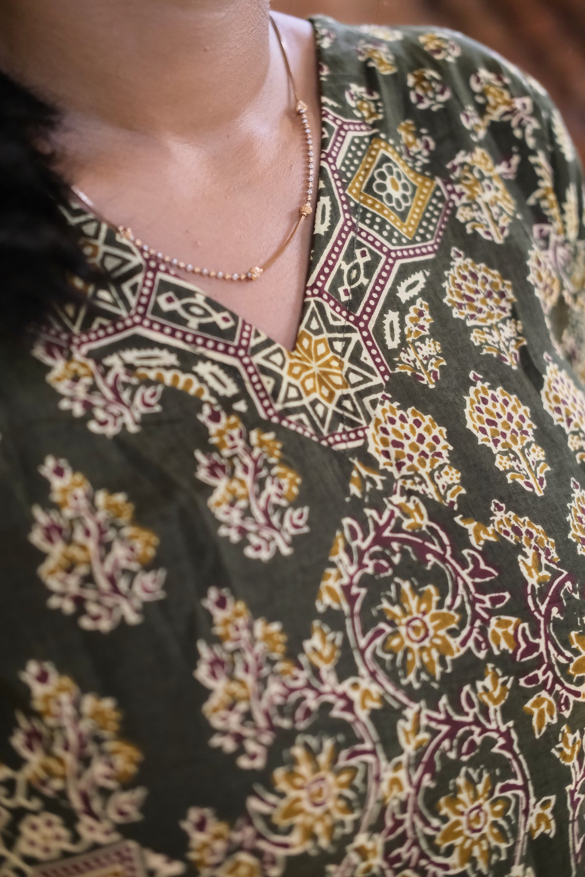 Close-up of the crossover V-neckline on the olive green printed cotton nighty