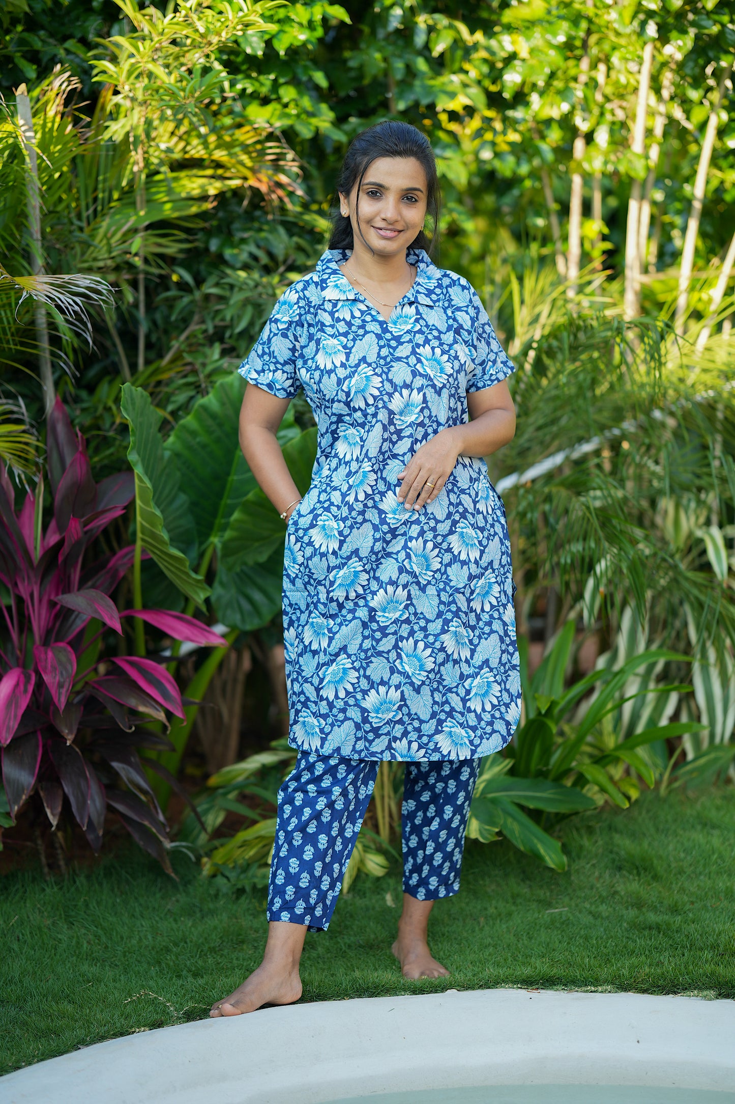 Blue ladies cotton night suit featuring a collared top with side pockets and ankle-length pants.