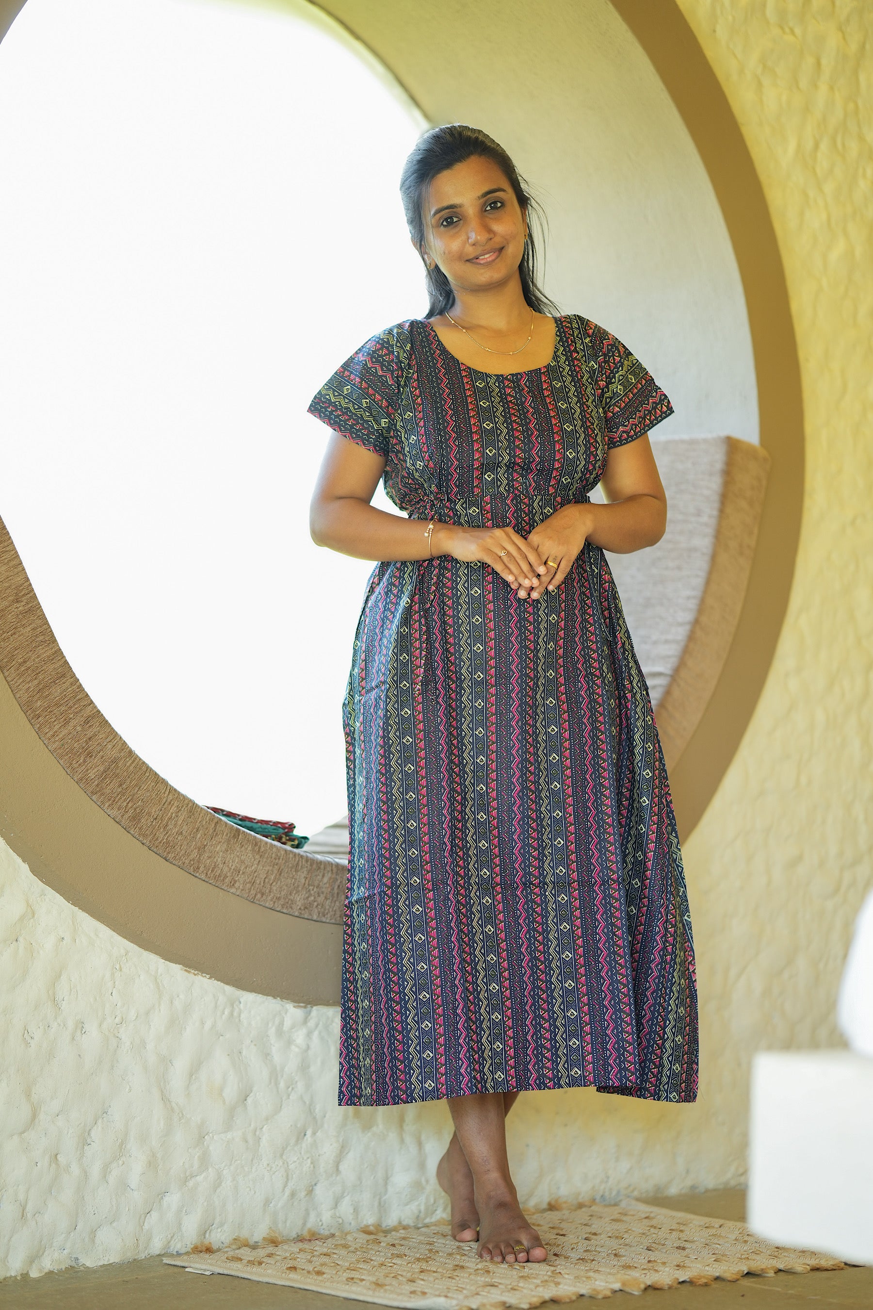 Ankle length navy blue cotton nighty with pink and yellow geometric prints and a round neck.