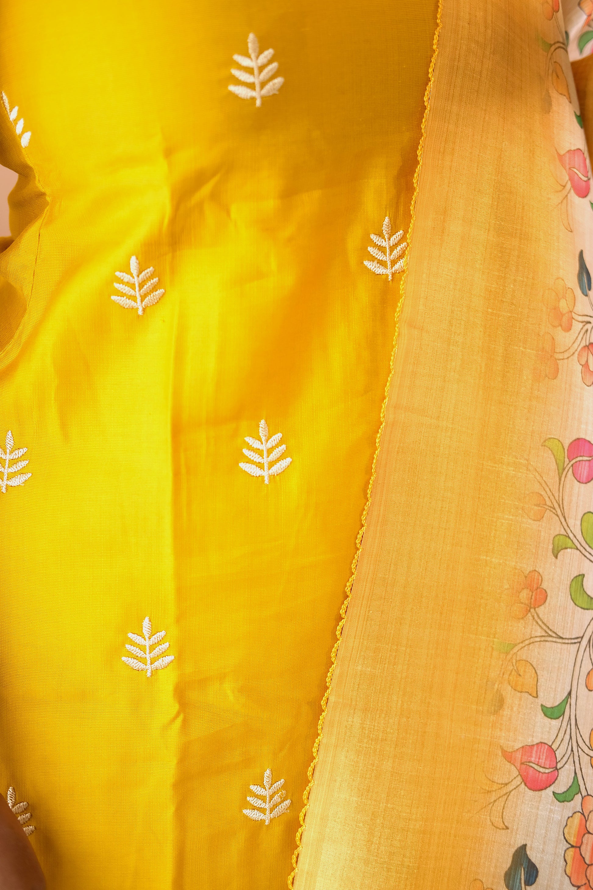 Detailed view of the white leaf embroidery on the yellow silk-blend fabric of the feeding friendly kurta set.