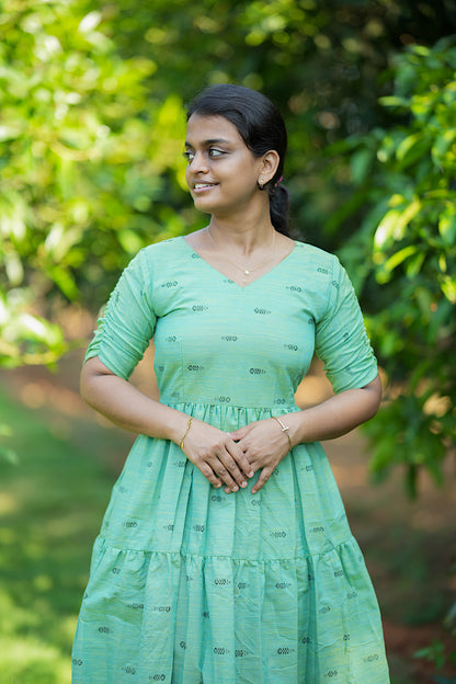 Close-up of the V-neckline and printed motifs on the green cotton maxi dress
