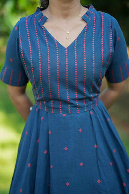Close-up of the V-neckline, stand collar, and red geometric print details on the blue cotton dress.