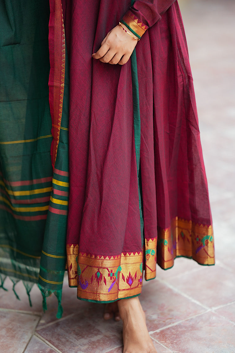 Close-up of the flared hemline of the maroon cotton anarkali with woven peacock motifs.