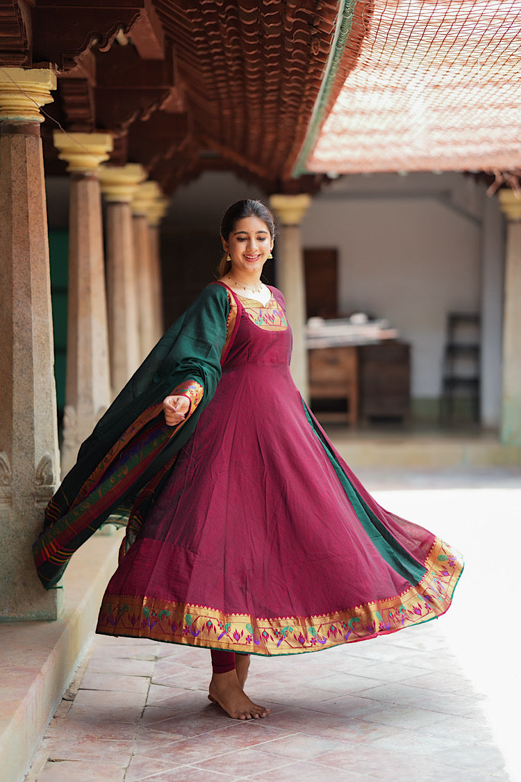 Twirling view of the flared maroon cotton anarkali suit set with rich zari hemline.