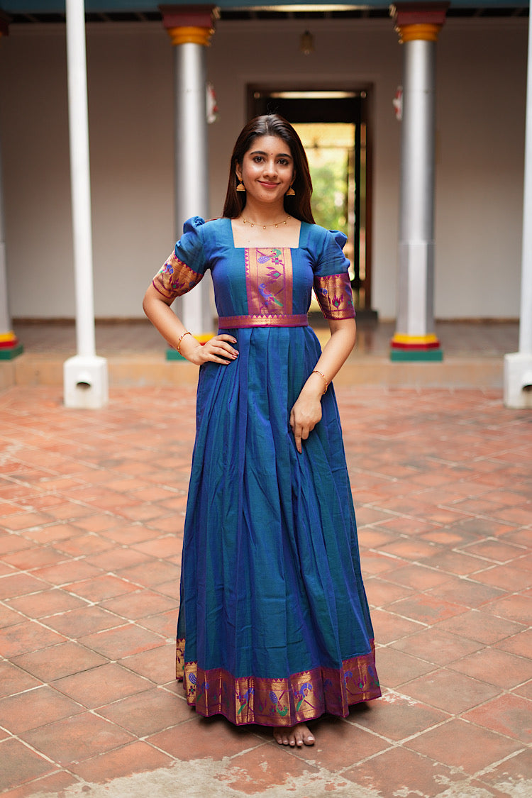 Front view of the peacock blue pleated ethnic gown with hands on waist showing the flared skirt.