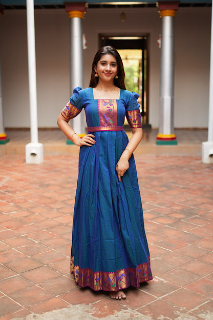 Front view of the peacock blue pleated ethnic gown with hands on waist showing the flared skirt.