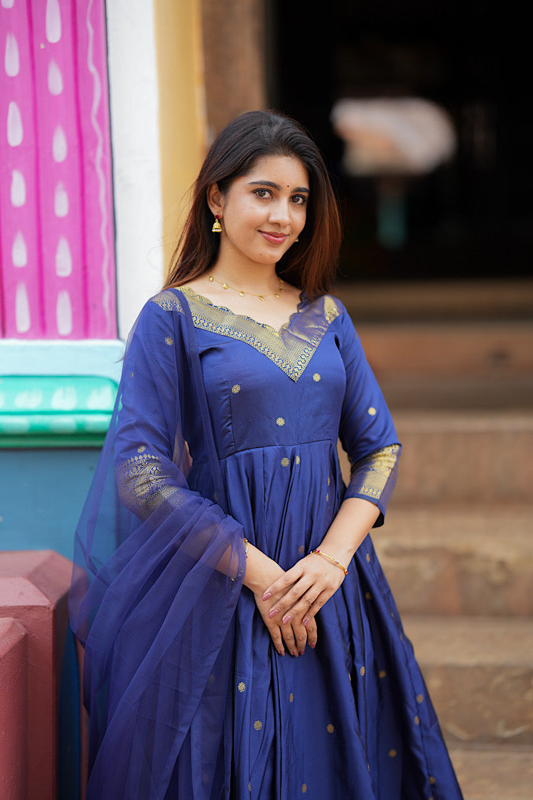 Elegant pose showcasing the rich royal blue silk fabric and gold woven motifs of the anarkali dress