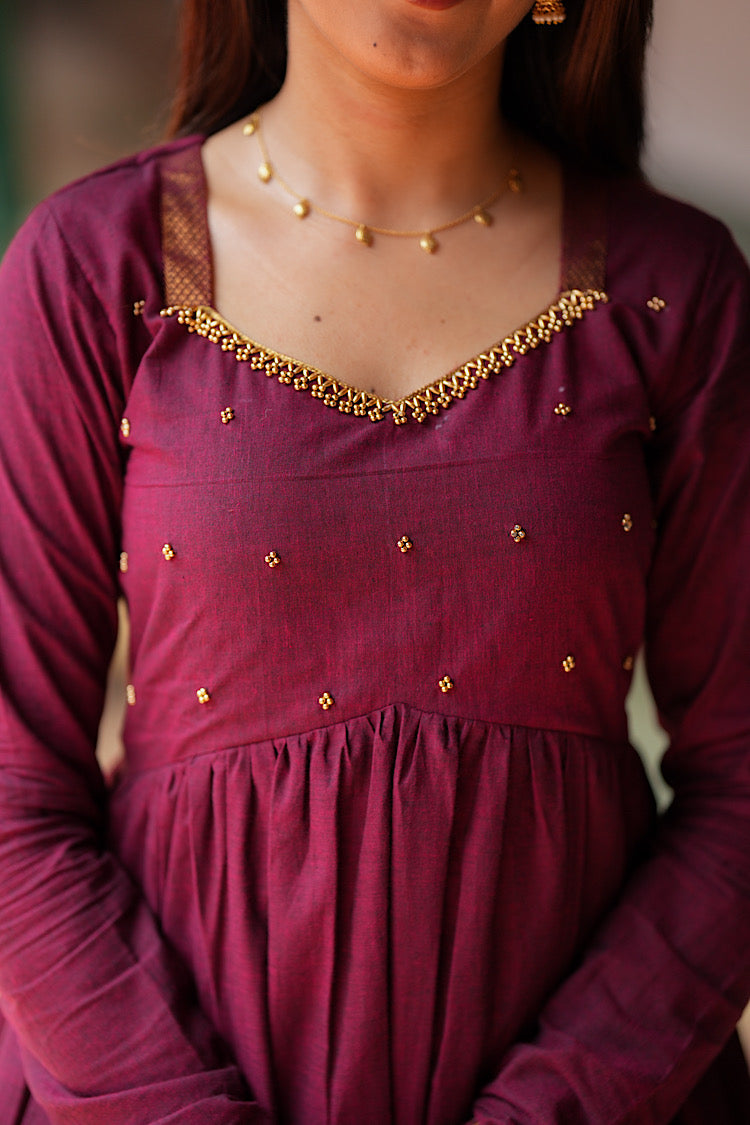 Close-up of the sweetheart neckline with gold Aari embroidery and bead buttas on the maroon kurti