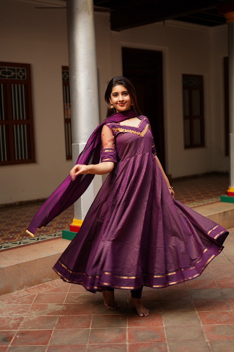 Twirling view of the flared purple anarkali suit set showing the wide zari border at the hem.