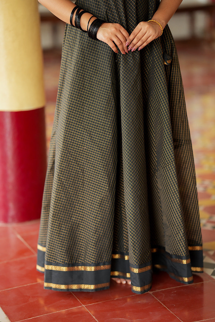 Flared skirt hem of the black Aarani silk maxi dress showing the gold border