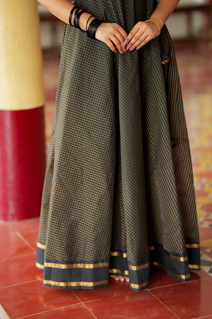 Flared skirt hem of the black Aarani silk maxi dress showing the gold border