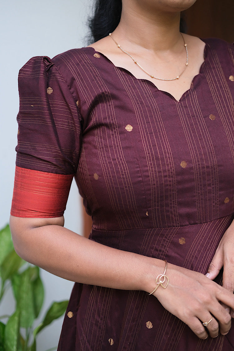 Close-up of the scalloped V-neckline and puff sleeves on the coffee brown festive long dress.