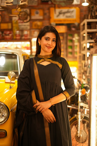Close-up of the keyhole neckline with gold zari border on a black anarkali suit set.