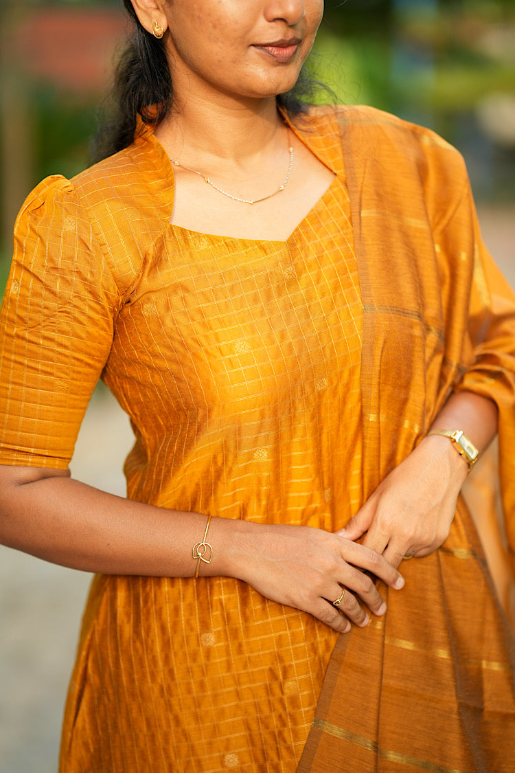 Close up of structured Queen Anne neckline on mustard yellow raw silk suit set