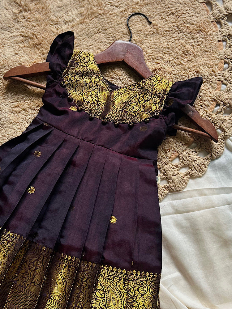 coffee brown pattu frock close up featuring paisley yoke and dangling potli balls
