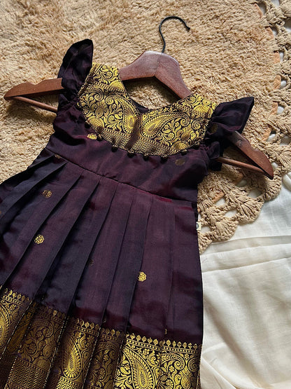 coffee brown pattu frock close up featuring paisley yoke and dangling potli balls