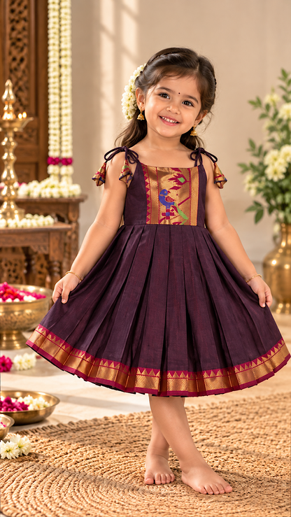 Little girl wearing brown pattu frock for baby girl with woven peacock motif yoke