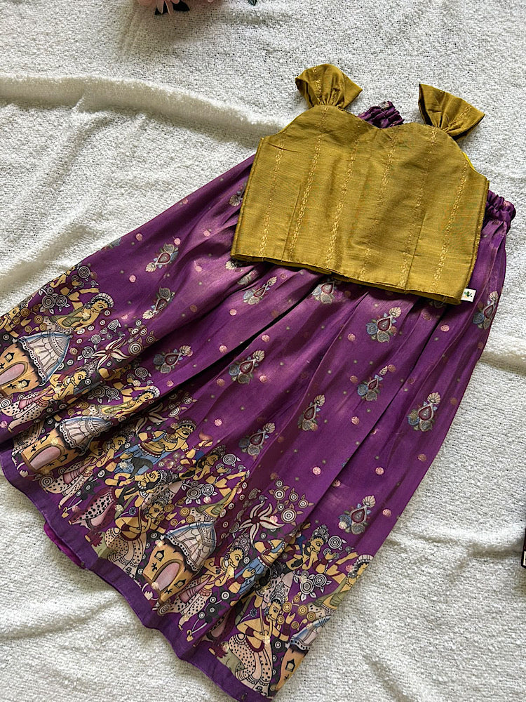 Flat lay of mustard raw silk top and purple printed kids lehenga skirt
