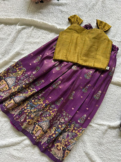 Flat lay of mustard raw silk top and purple printed kids lehenga skirt