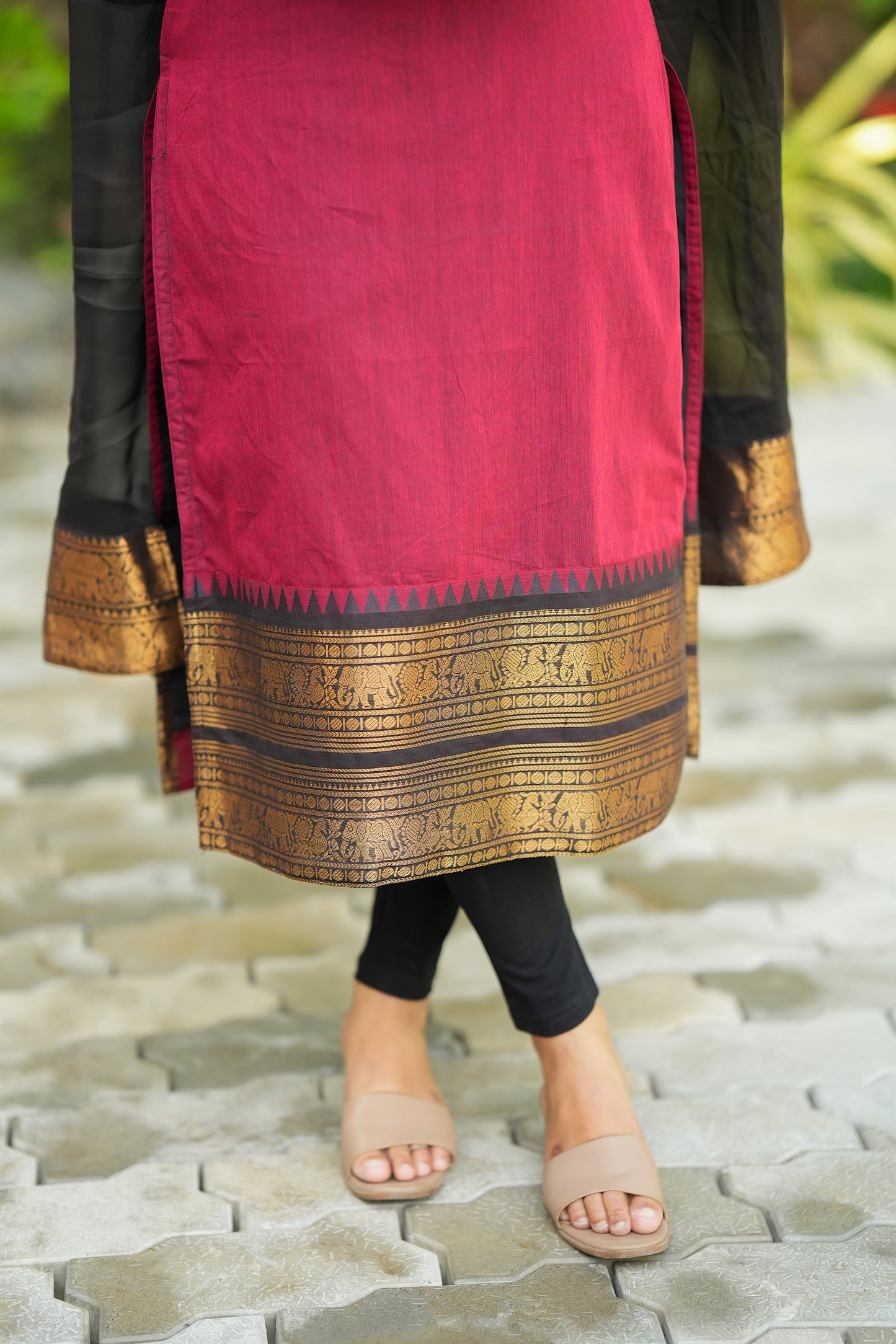 Close-up of the intricate gold zari border with elephant motifs on the hemline of the red cotton kurti.
