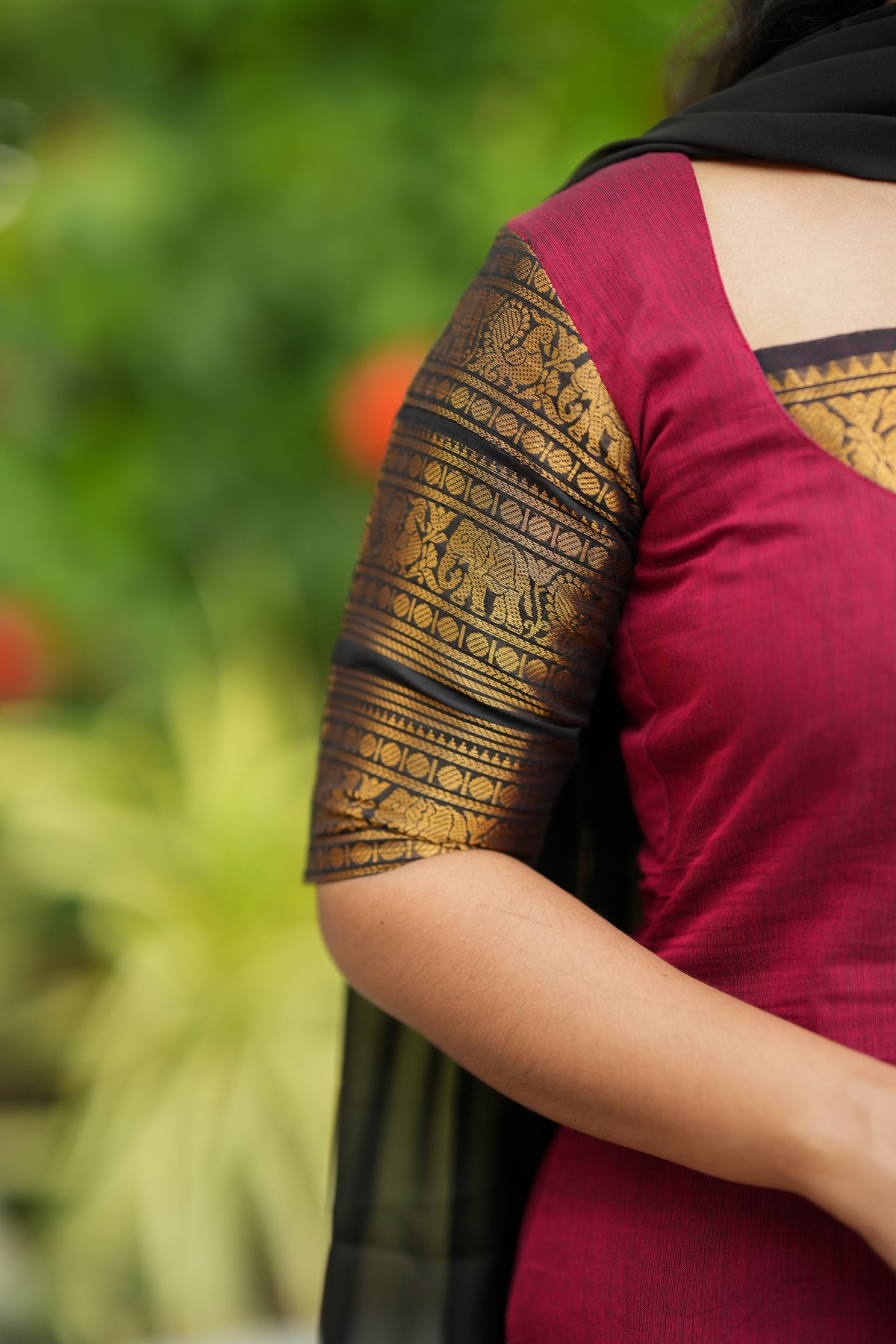 Detailed view of the sleeve featuring rich gold zari work on the red Chettinad cotton kurti.