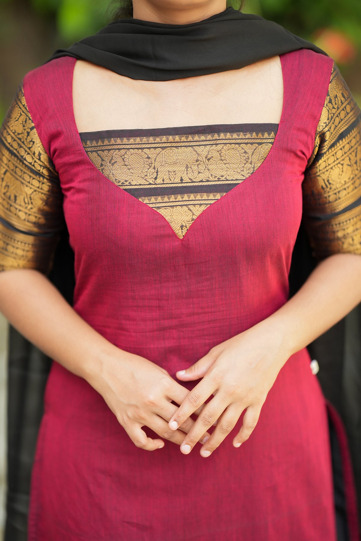 Close-up of the neckline and yoke design with traditional gold zari borders on the red cotton kurti.
