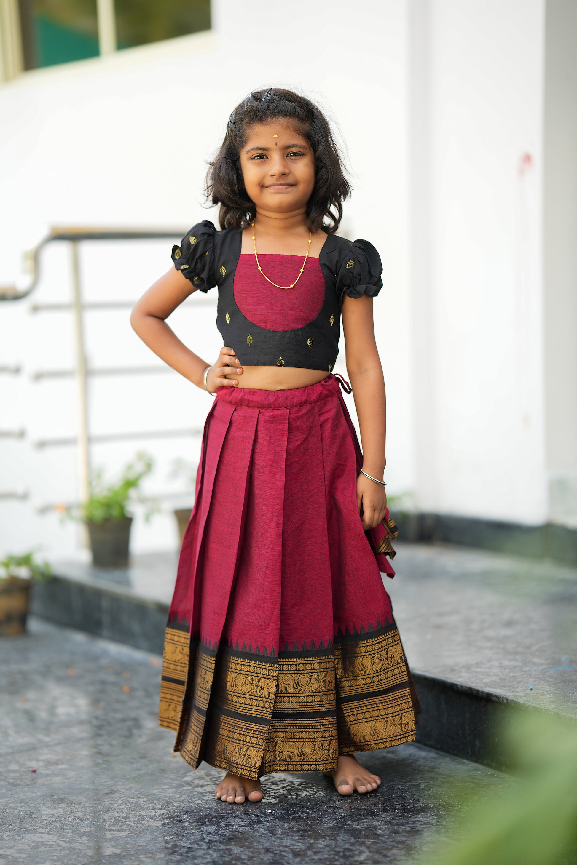 Elamathi red and black kids pattu pavadai featuring traditional zari border and pleated skirt