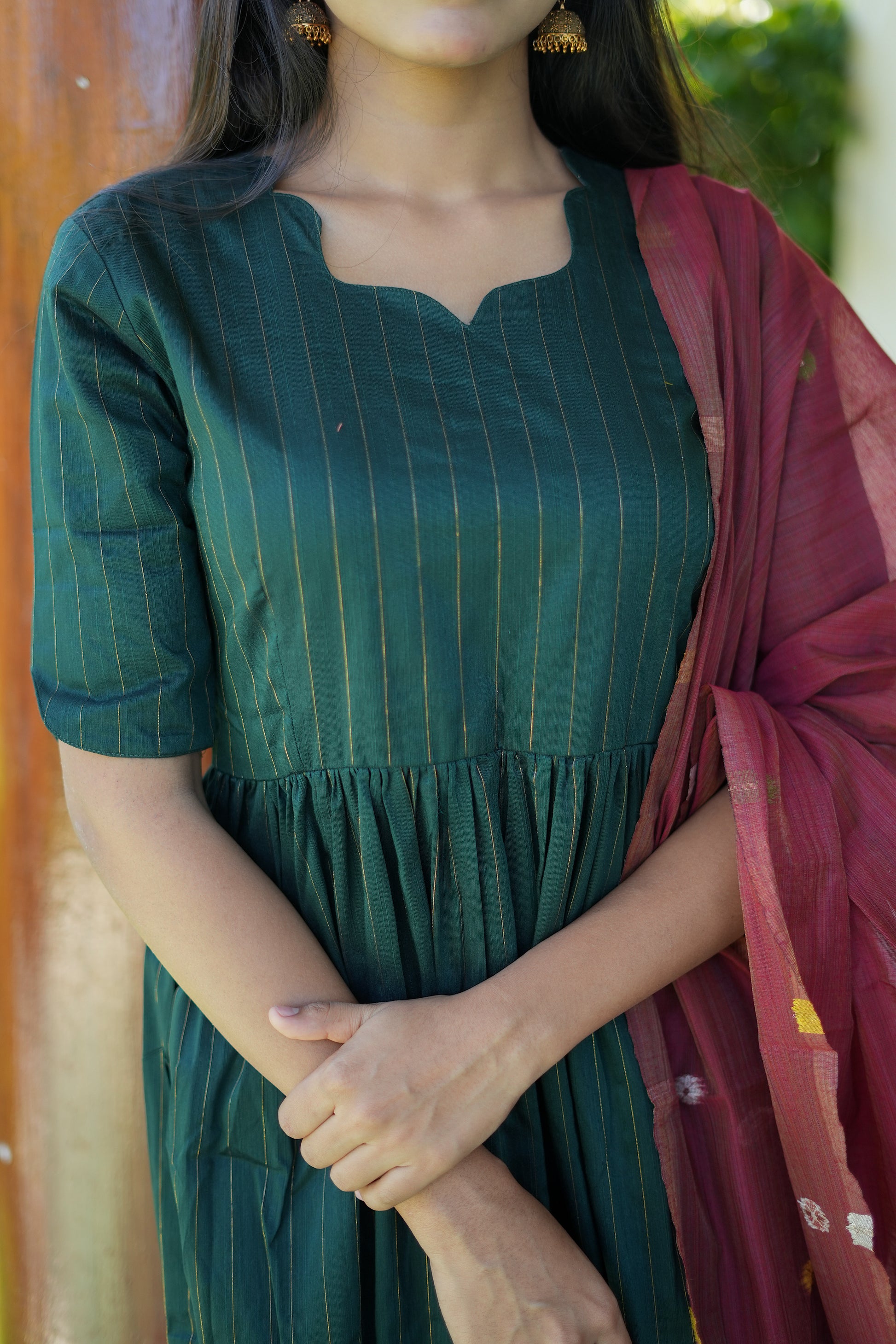 Detailed view of the notched neckline and gathered empire waist of the bottle green raw silk kurta.