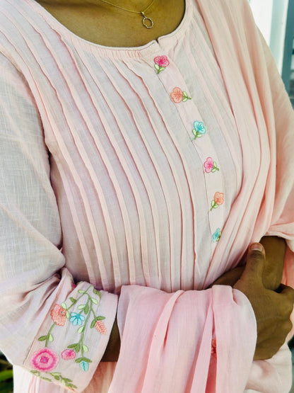 Close-up of the pin tucks and colorful floral embroidery on the neckline and sleeves of the pink cotton kurti.