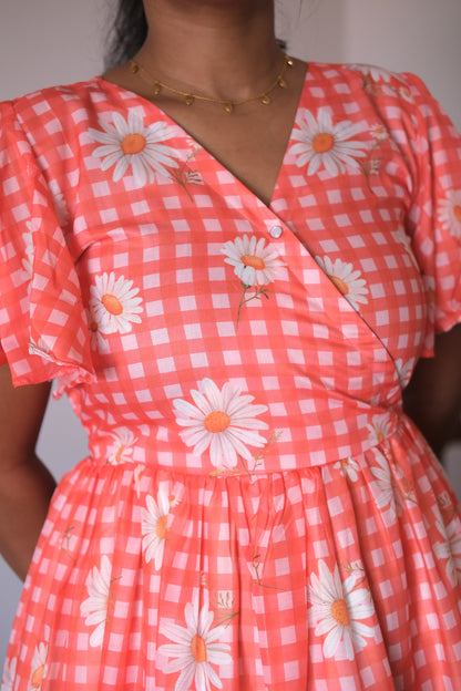 Close-up of the coral gingham and white daisy floral print on a cotton midi dress.