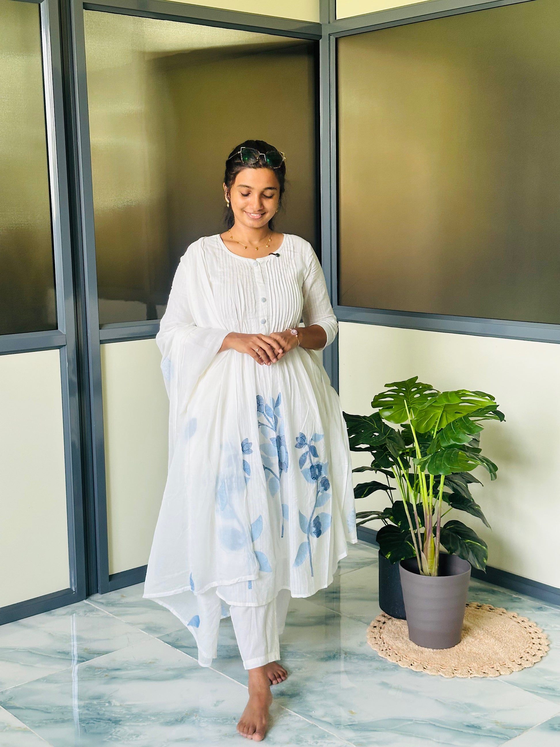 Close-up of the white embroidered kurti set showing the pin-tuck yoke, button accents, and round neckline