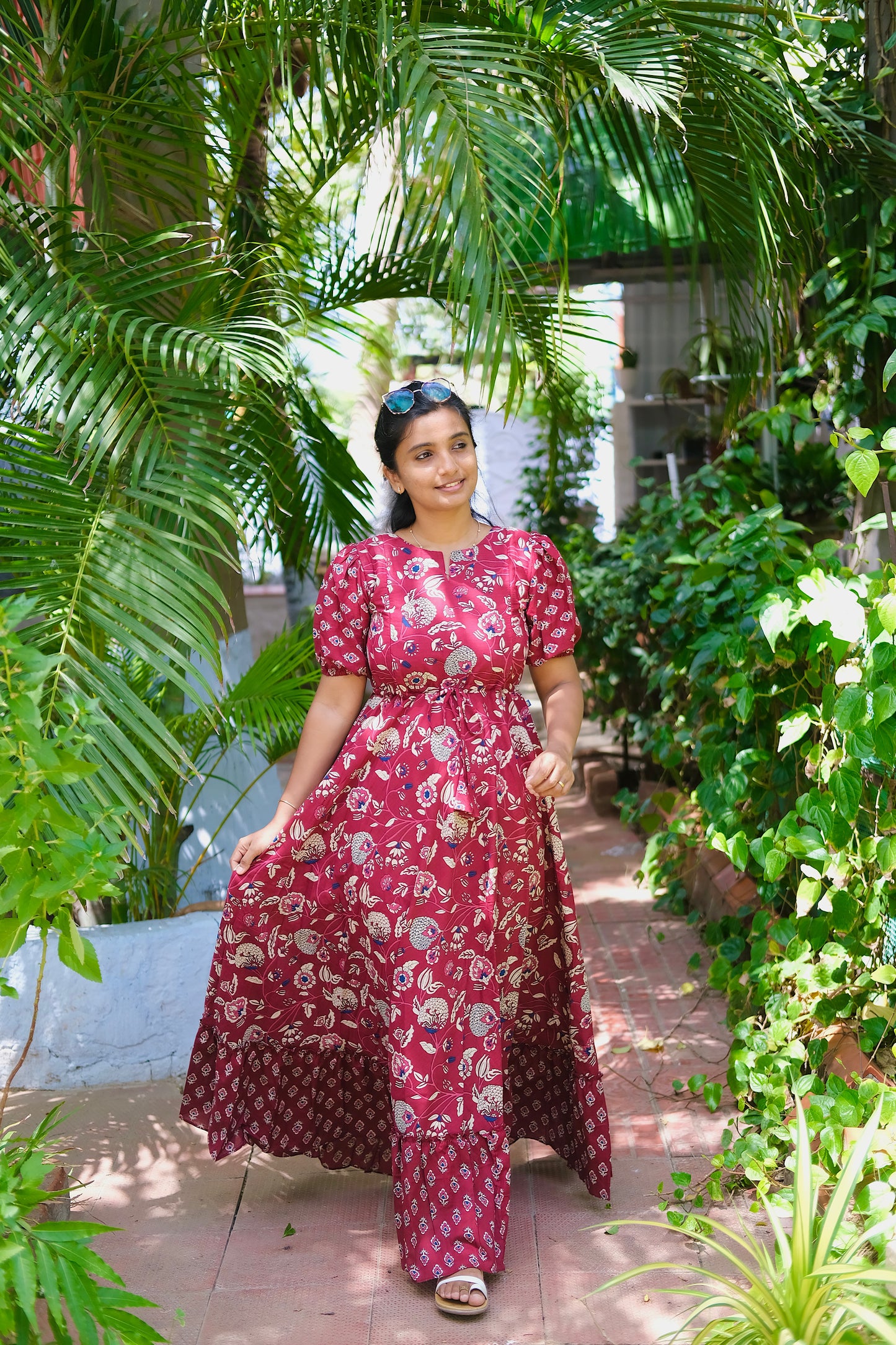 A woman walking in a long cotton dress in maroon with floral prints