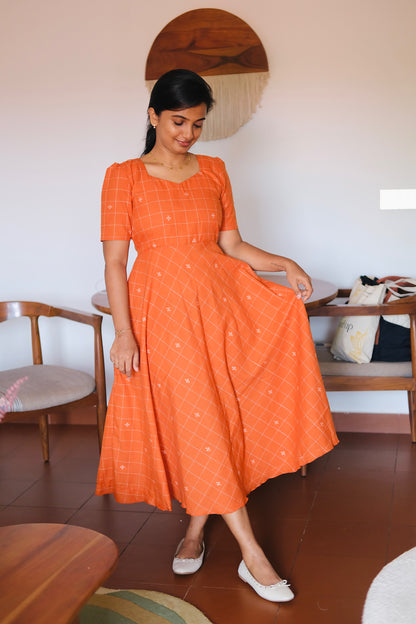 Short-sleeved rust orange patterned midi dress with a sweetheart neckline and check print.