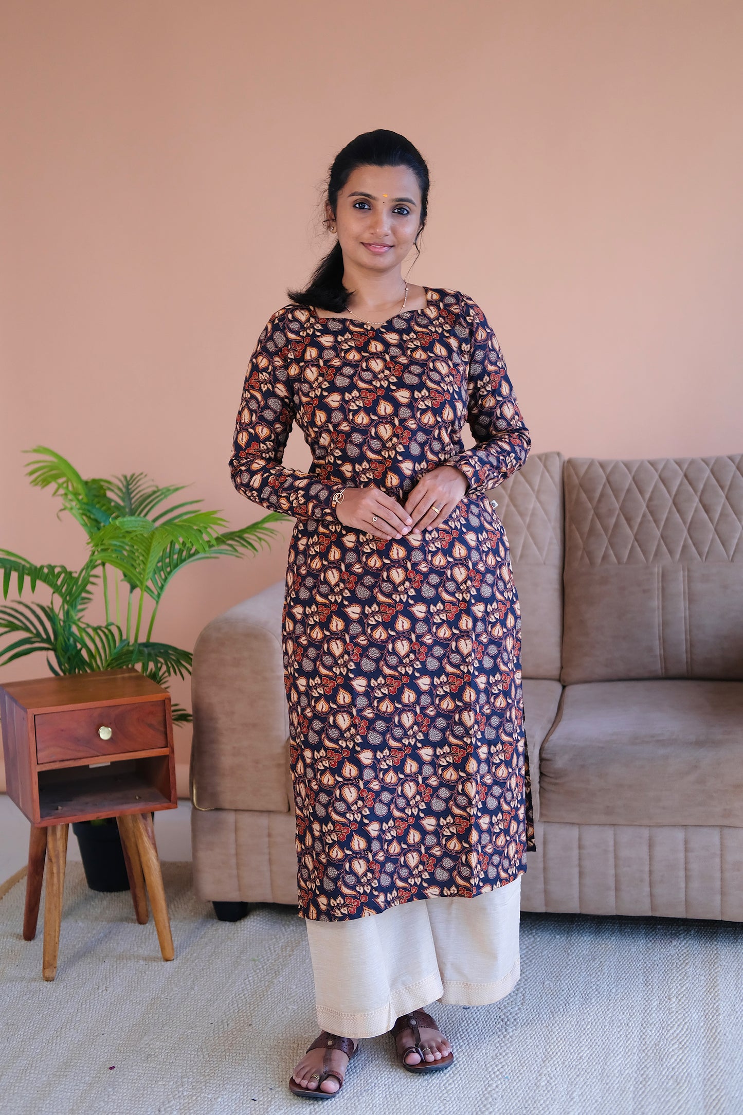 Close-up of the round neckline and intricate rust and beige print on the black cotton straight kurti.