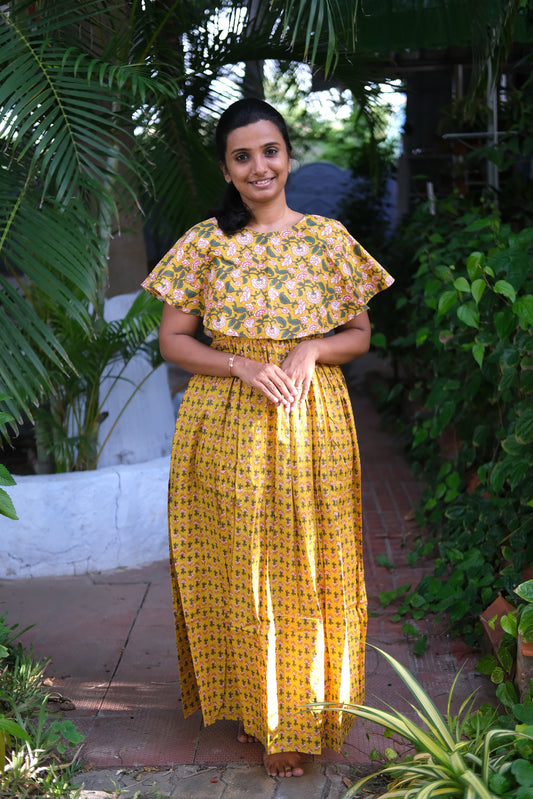 Mustard yellow ladies cotton nighty featuring a pink floral print cape yoke and a gathered maxi-length skirt.