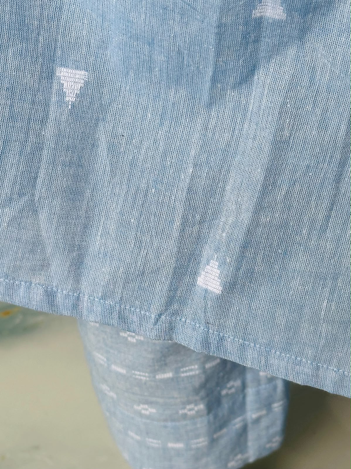 Close-up of the textured sky blue handloom cotton fabric showing the woven white patterns and hemline.
