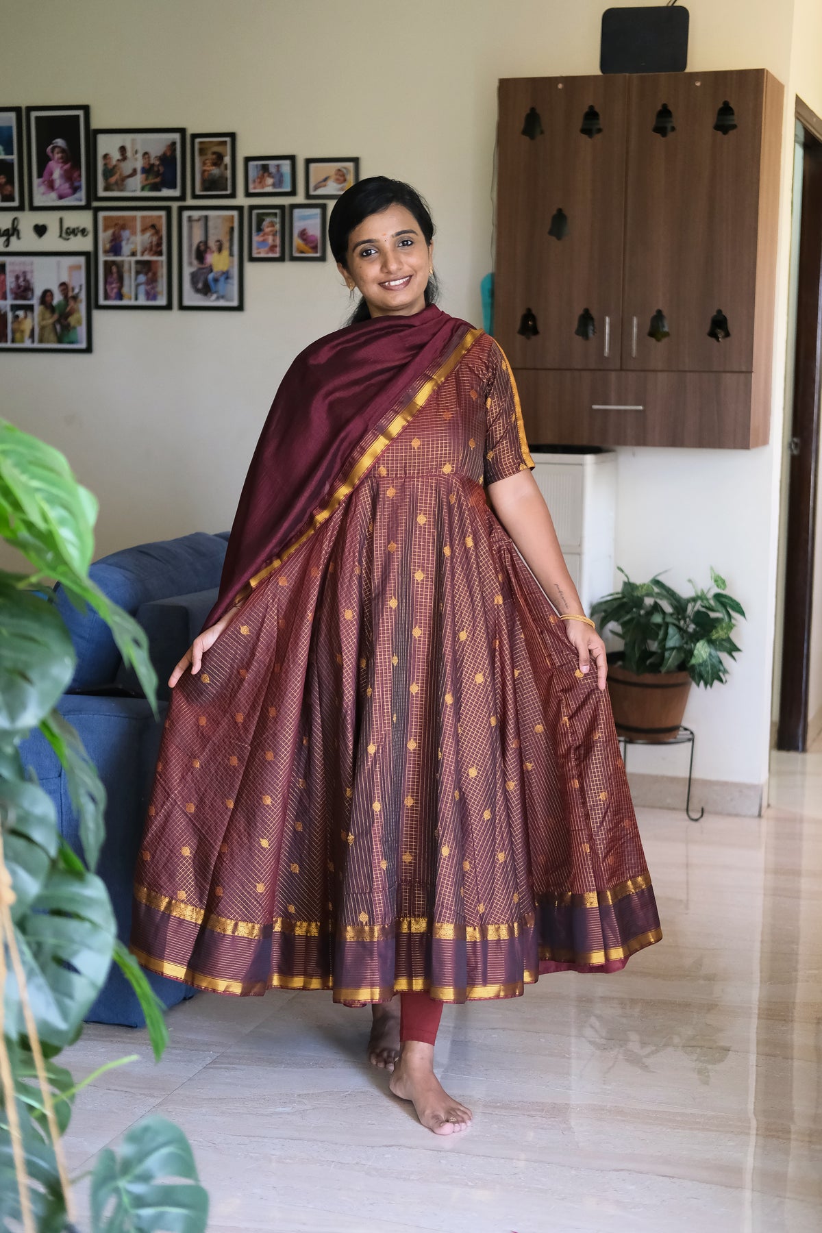 Full flare view of golden maroon silk anarkali dress paired with a rich zari border dupatta