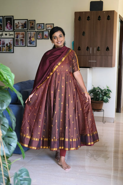 Full flare view of golden maroon silk anarkali dress paired with a rich zari border dupatta