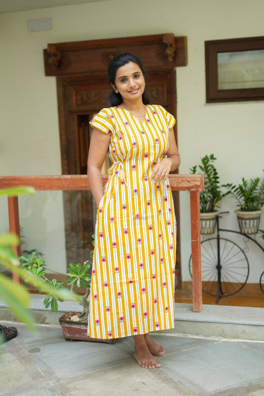 Mustard yellow and white striped cotton nighty for women with pink floral prints, featuring a V-neck and side tie waist.