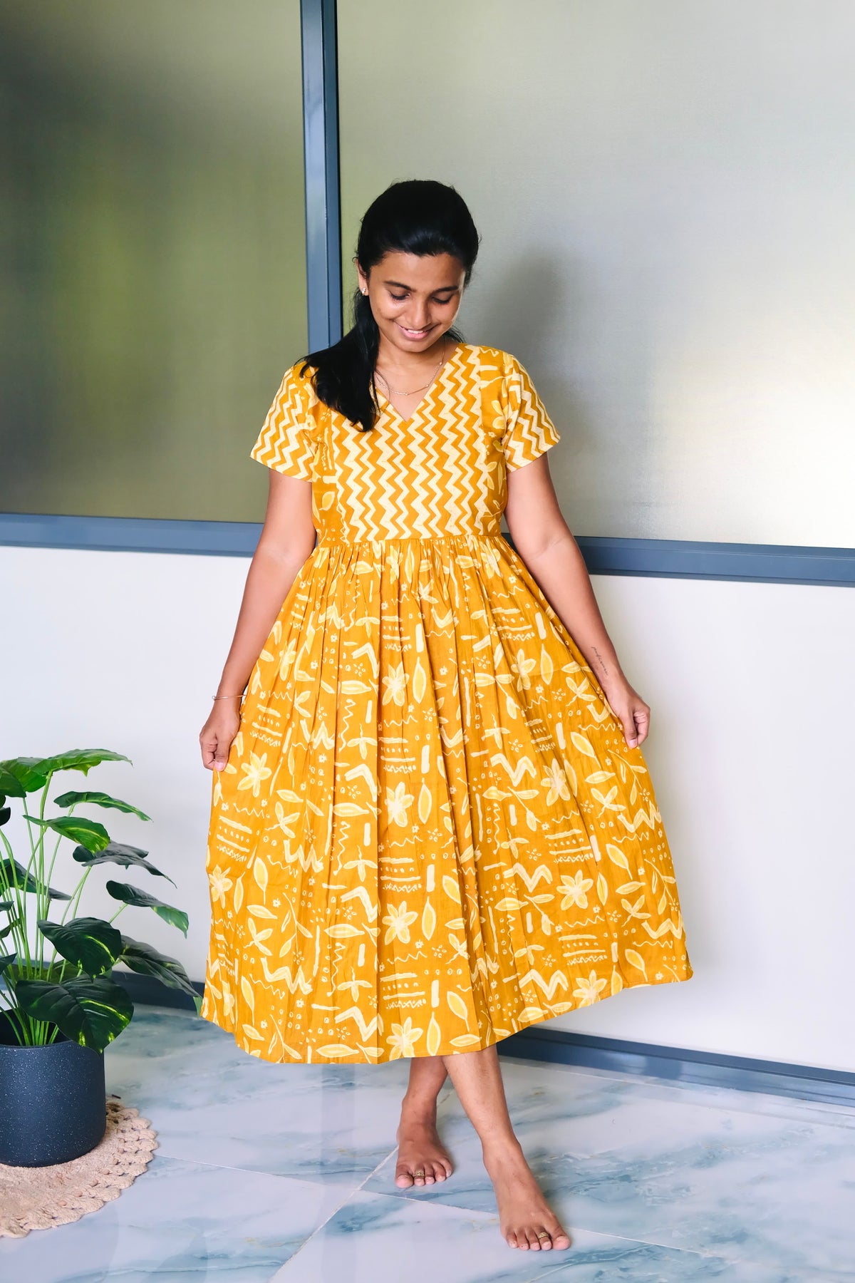 A comfortable ladies cotton nighty in mustard yellow with abstract floral prints and short sleeves.