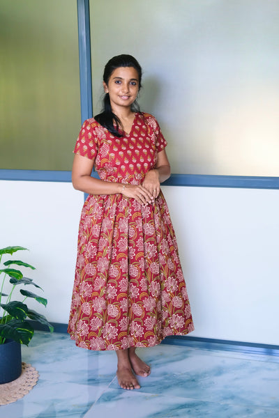 A red cotton midi nighty with white and green floral block prints, featuring a gathered waist and short sleeves.