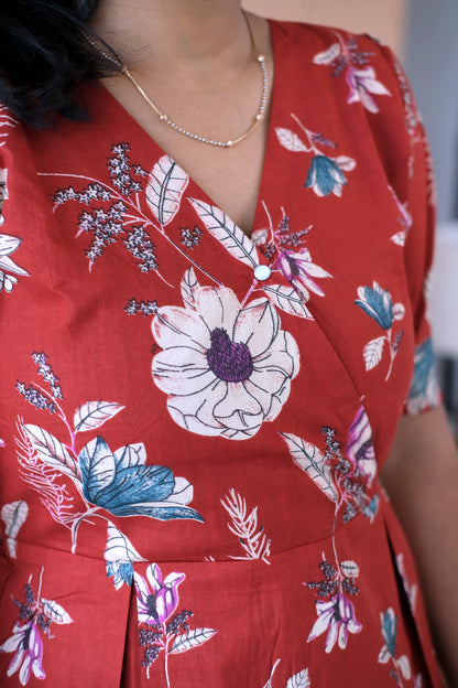 Close-up of the wrap-style V-neckline and floral pattern on the red cotton midi nighty.